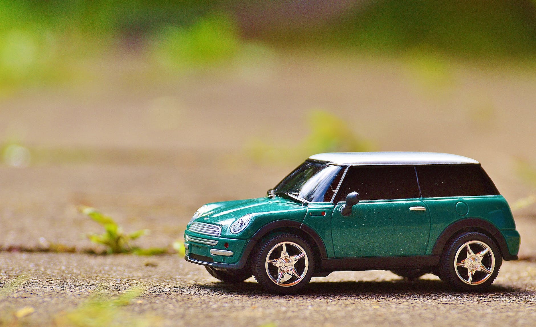 green scale model car on brown pavement